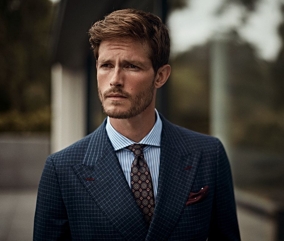 Senszio model in a navy check suit jacket, blue and white pinstripe shirt and a floral statement tie with complimenting pocket square