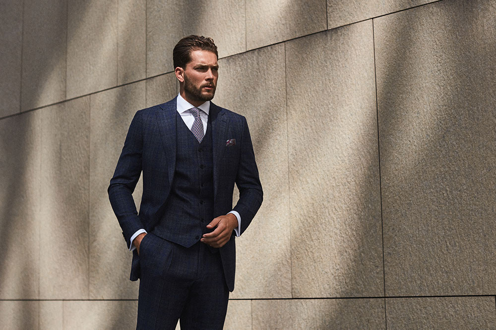 Model wearing sophisticated three-piece suit in dark navy, custom made to measure by Senszio