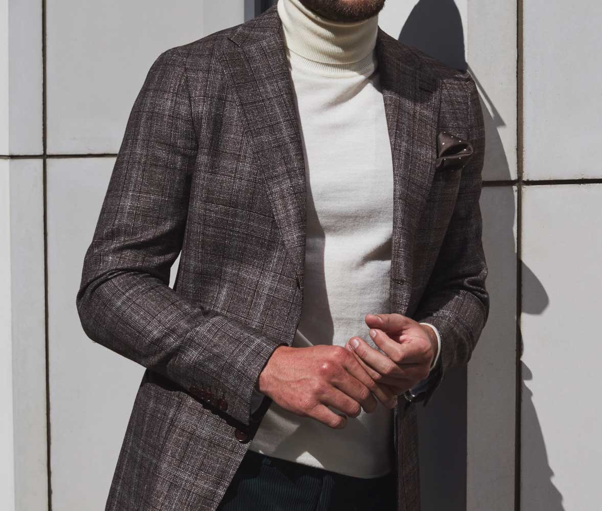 Man in custom tailor check print casual sports jacket, worn over a smart cream roll-neck sweater